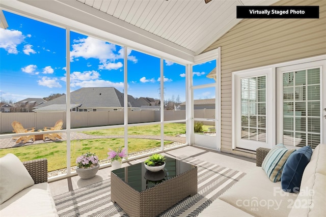 sunroom with wooden ceiling, a residential view, vaulted ceiling, and a wealth of natural light