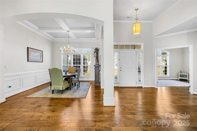 foyer entrance with coffered ceiling, a healthy amount of sunlight, and hardwood / wood-style floors