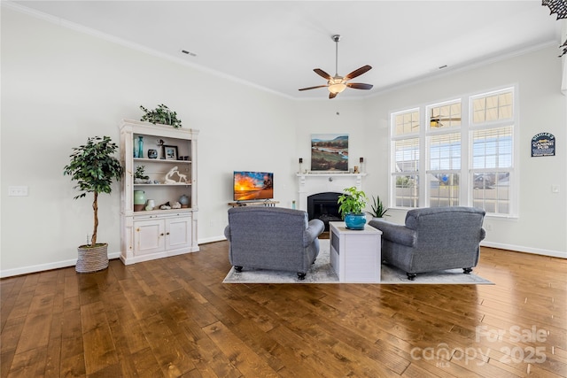 living area with hardwood / wood-style floors, a glass covered fireplace, visible vents, and crown molding