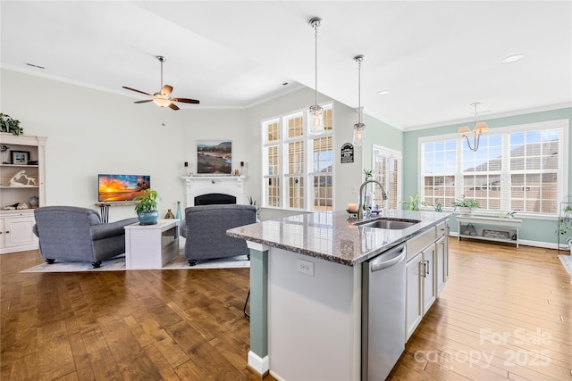 kitchen featuring hardwood / wood-style flooring, a sink, crown molding, a fireplace, and stainless steel dishwasher