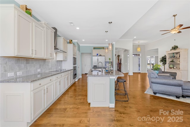 kitchen featuring arched walkways, a breakfast bar, tasteful backsplash, open floor plan, and a sink