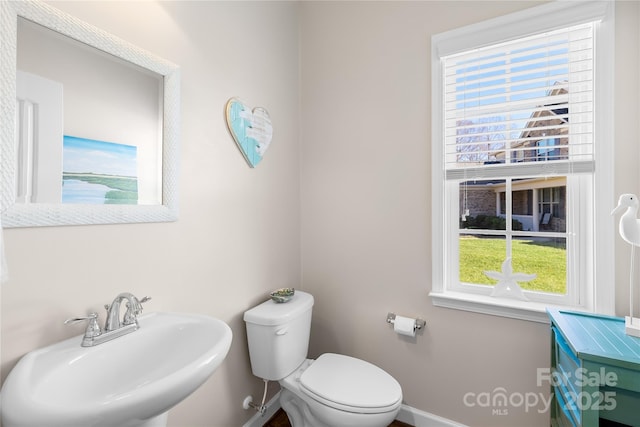 bathroom featuring baseboards, a sink, and toilet