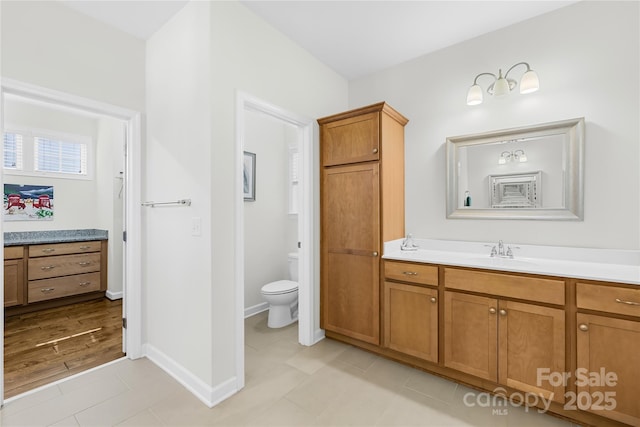 bathroom featuring toilet, vanity, and baseboards