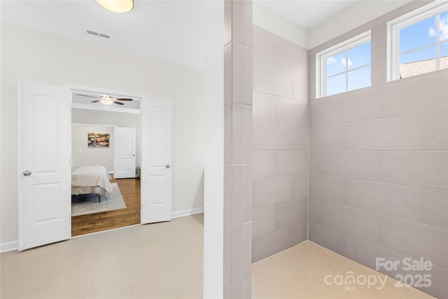 ensuite bathroom featuring baseboards, visible vents, tiled shower, and ensuite bathroom