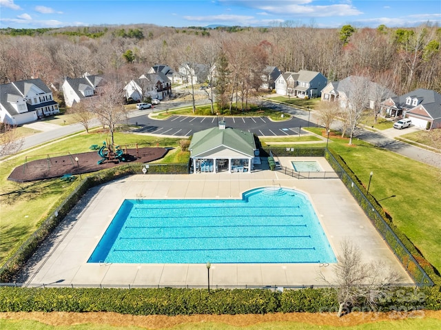 view of pool with a lawn, fence, and a residential view