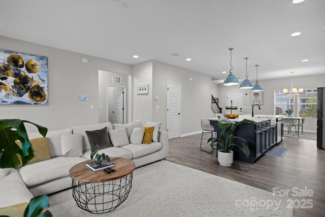 living room with a chandelier, sink, and dark wood-type flooring