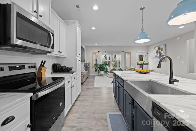 kitchen with sink, white cabinetry, pendant lighting, stainless steel appliances, and light stone countertops