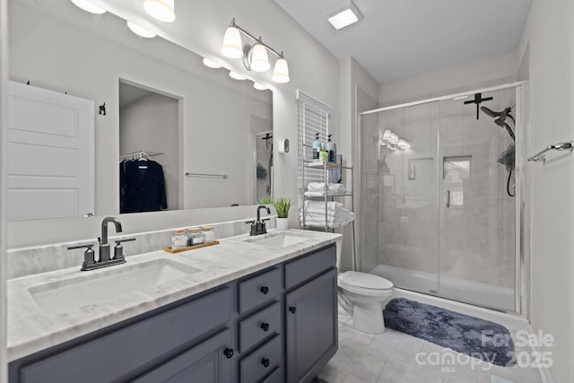 bathroom featuring tile patterned floors, toilet, vanity, and a shower with shower door