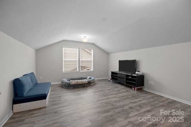 sitting room with light wood-type flooring and vaulted ceiling