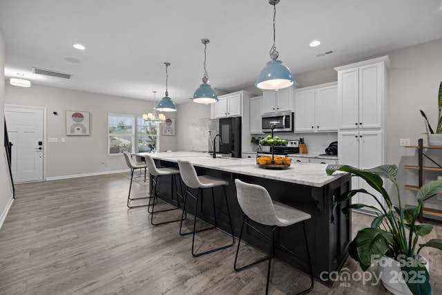 201 Bennett Trail Dr, Mount Holly, NC 28120 - kitchen with stainless steel appliances, decorative backsplash, white cabinetry, a large island with sink, and a kitchen bar