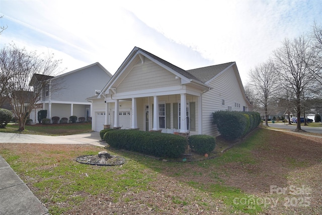 view of front of property featuring a front lawn, a garage, driveway, and a porch