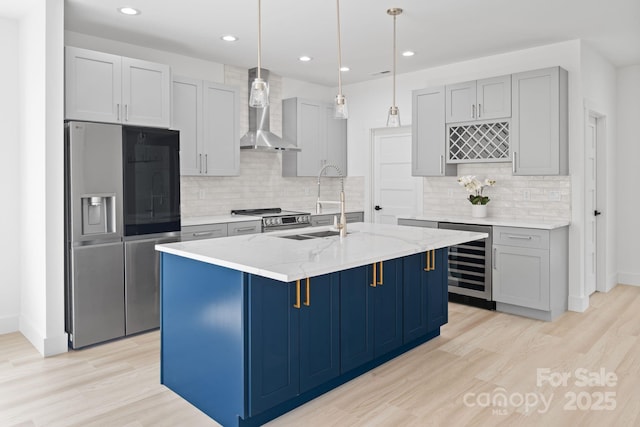 kitchen with stainless steel appliances, beverage cooler, wall chimney exhaust hood, and light wood-type flooring