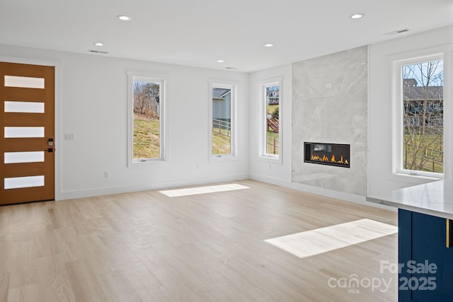 unfurnished living room featuring recessed lighting, a wealth of natural light, and light wood finished floors
