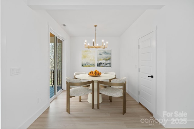dining room with plenty of natural light, light wood-style floors, baseboards, and a notable chandelier