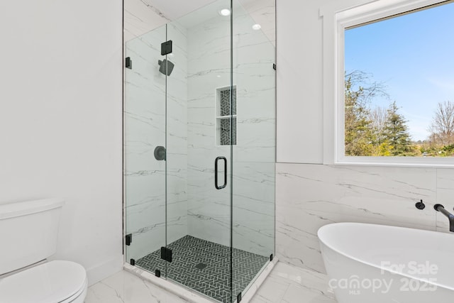 full bathroom with toilet, a freestanding tub, a healthy amount of sunlight, and marble finish floor