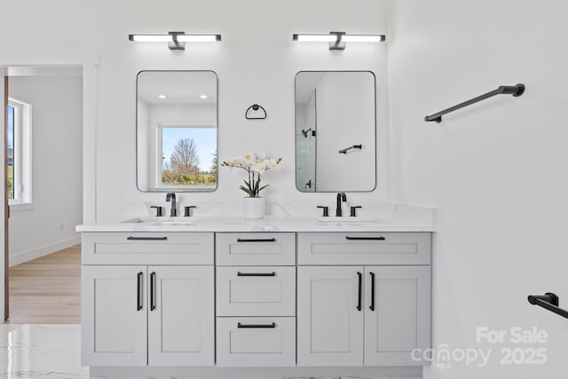full bathroom featuring a sink, double vanity, and a healthy amount of sunlight