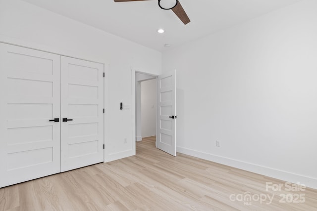 unfurnished bedroom with light wood finished floors, a closet, baseboards, and recessed lighting
