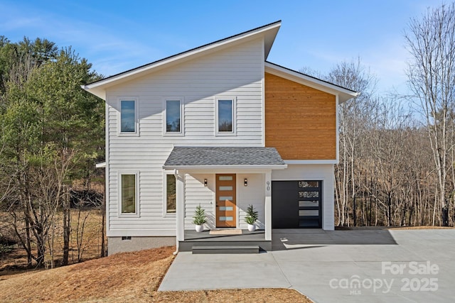 modern home with an attached garage, concrete driveway, and a shingled roof
