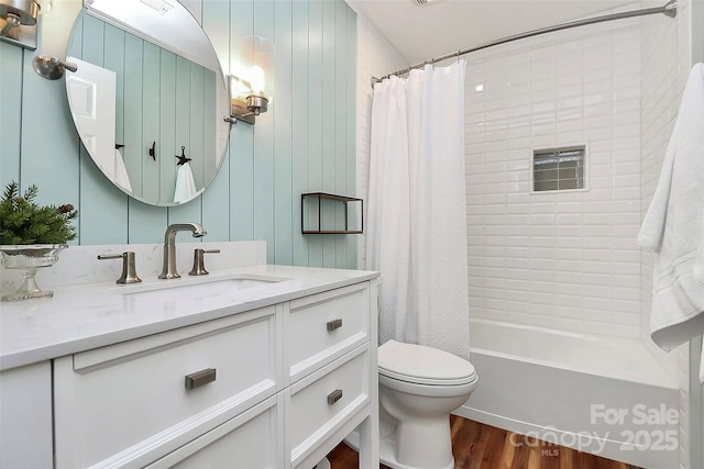 bathroom featuring toilet, shower / bath combination with curtain, wood finished floors, and vanity