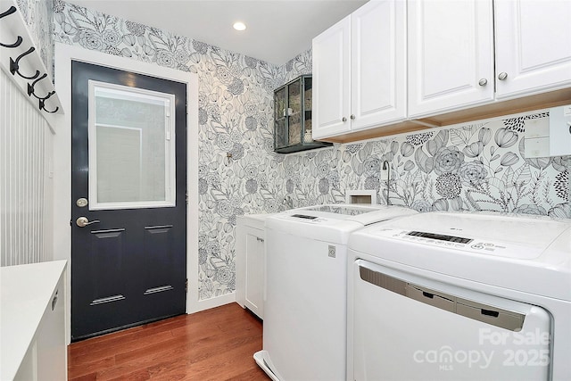 washroom with dark wood-type flooring, independent washer and dryer, cabinet space, and wallpapered walls