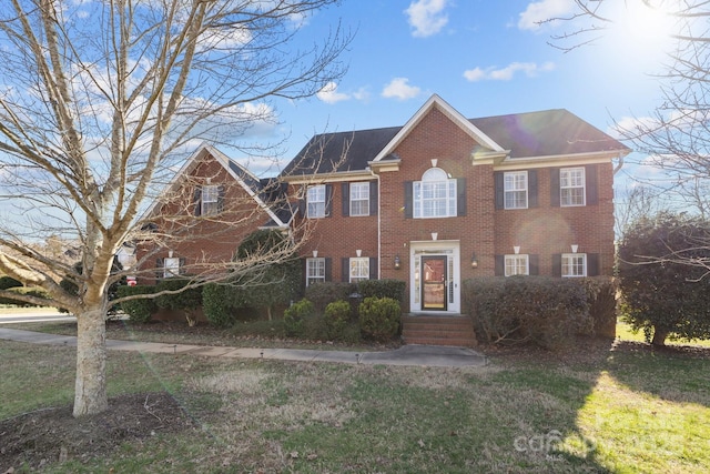 colonial home with brick siding and a front yard