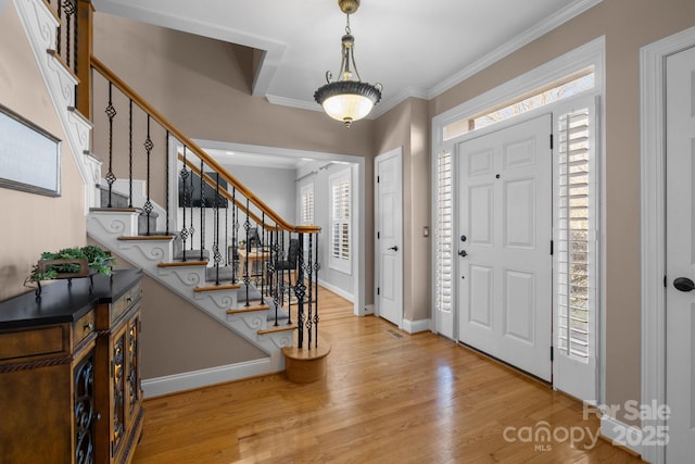 foyer with stairway, baseboards, ornamental molding, and wood finished floors