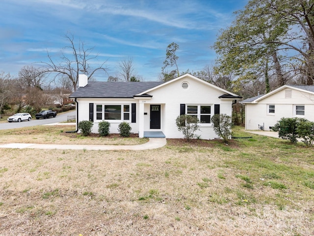 single story home featuring roof with shingles, a chimney, and a front lawn