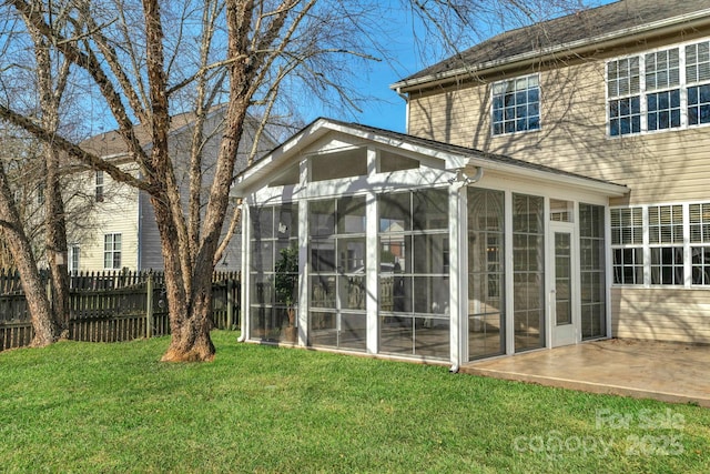 rear view of house featuring a patio, a sunroom, and a lawn