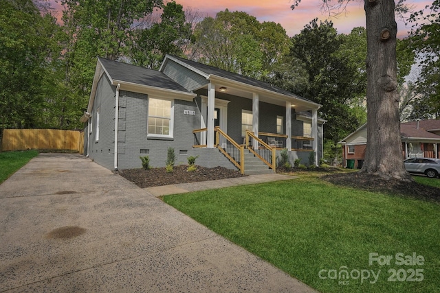 bungalow-style home with crawl space, driveway, brick siding, a porch, and a yard