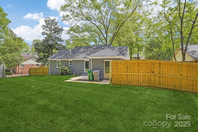 back of property with a yard, fence, and brick siding