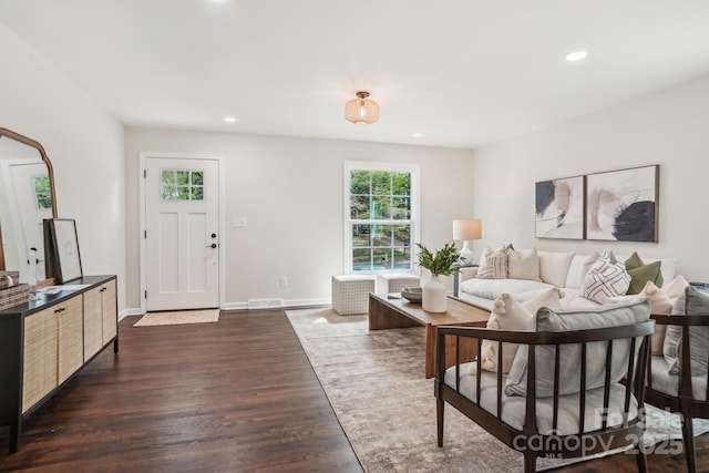 living room featuring recessed lighting, dark wood-type flooring, visible vents, and baseboards