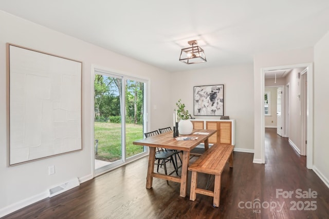 dining area featuring visible vents, baseboards, attic access, and dark wood finished floors