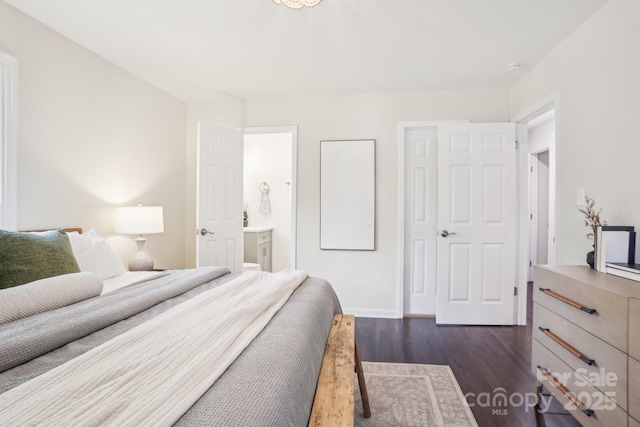 bedroom with baseboards, dark wood finished floors, and ensuite bath