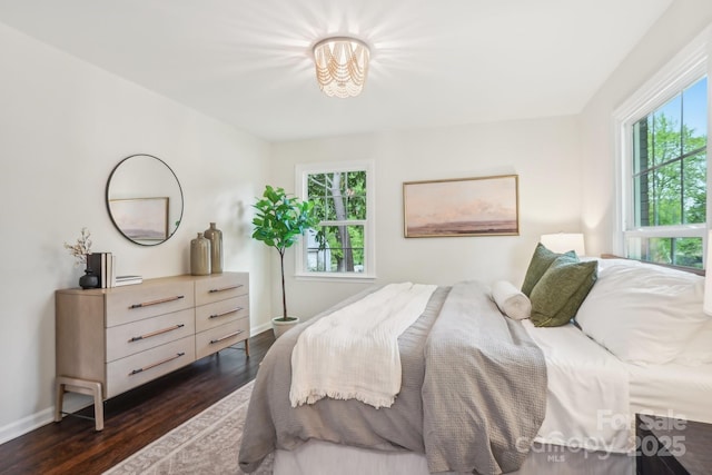 bedroom featuring an inviting chandelier, multiple windows, baseboards, and dark wood finished floors