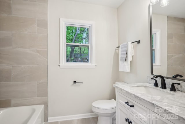 bathroom featuring toilet, vanity, and baseboards