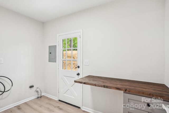 laundry room with baseboards, light wood finished floors, laundry area, and electric panel