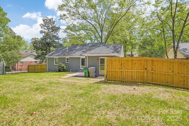 back of property featuring brick siding, fence, a patio area, and a lawn