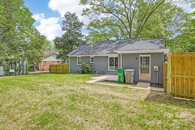 rear view of property with central AC, a yard, entry steps, fence, and brick siding