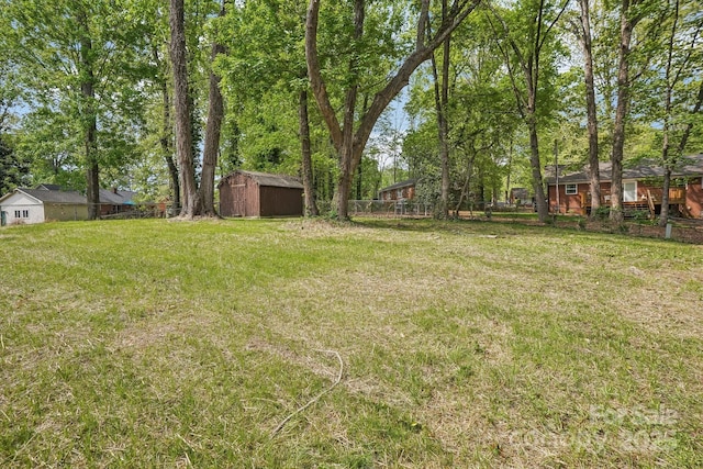 view of yard featuring an outbuilding, fence, and a shed