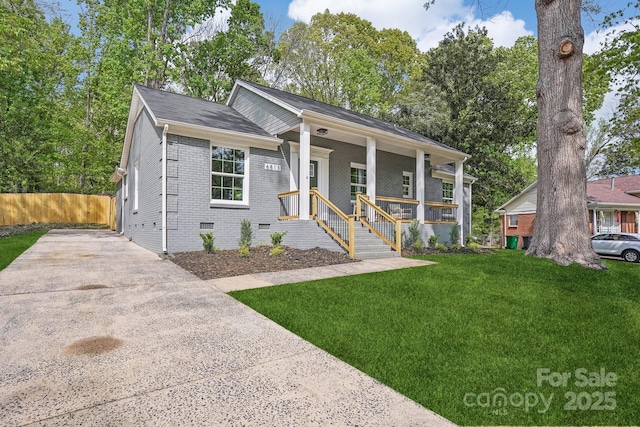 view of front of home with concrete driveway, crawl space, a front lawn, brick siding, and covered porch