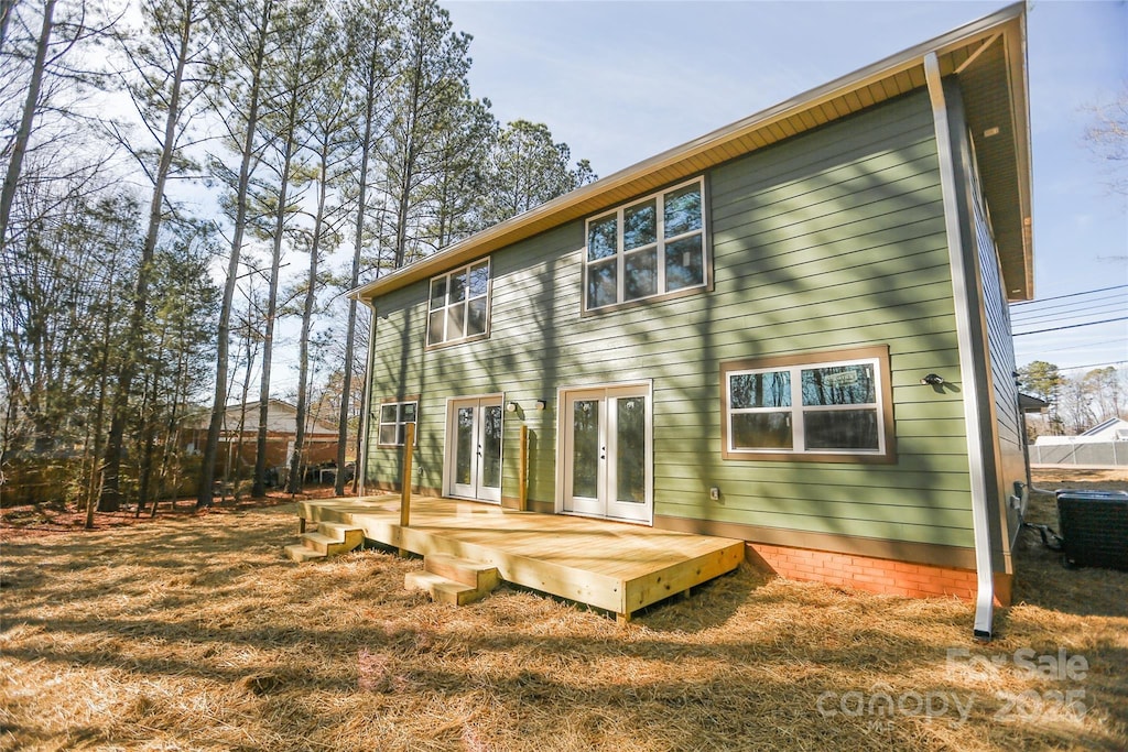 rear view of property featuring a wooden deck, central AC unit, french doors, and a lawn