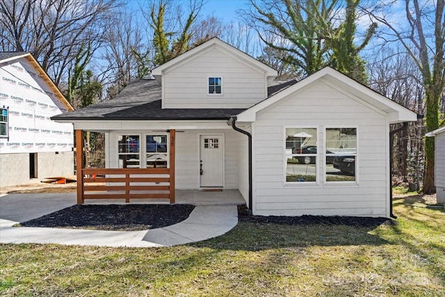 bungalow featuring a shingled roof, a front yard, and covered porch