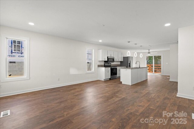 kitchen featuring visible vents, an island with sink, open floor plan, dark wood-type flooring, and stainless steel appliances