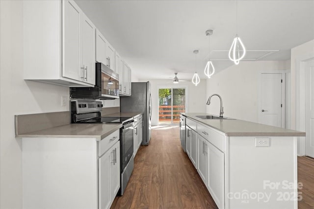 kitchen featuring white cabinets, dark wood-style flooring, stainless steel appliances, and a sink