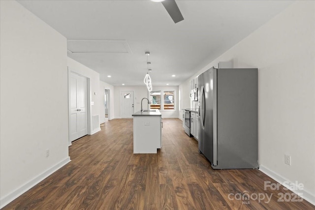 kitchen featuring dark wood finished floors, an island with sink, decorative light fixtures, stainless steel appliances, and a sink