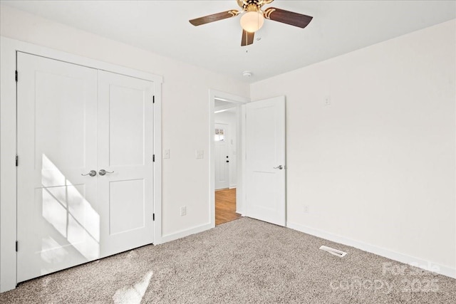 unfurnished bedroom with visible vents, baseboards, a ceiling fan, carpet, and a closet