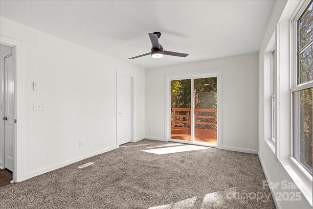 carpeted spare room featuring a ceiling fan and baseboards