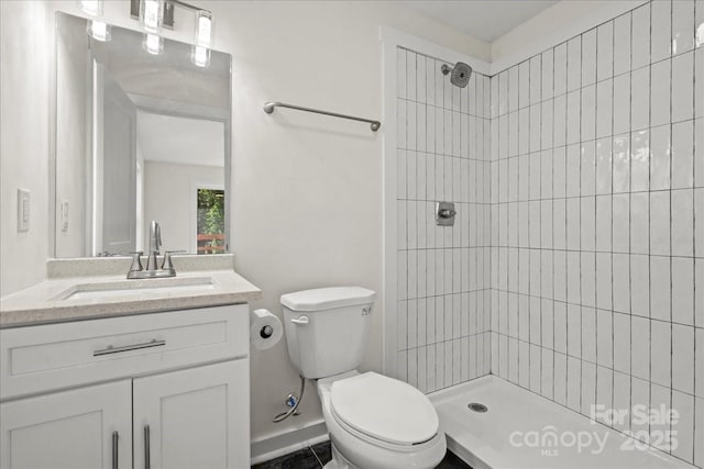 full bathroom with a tile shower, vanity, and toilet