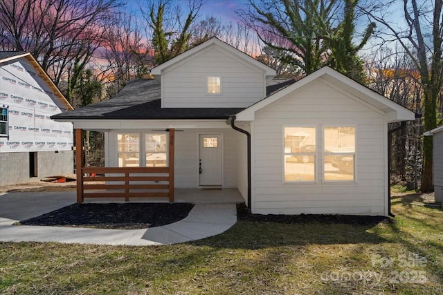 view of front of home featuring a porch, a front yard, and a shingled roof