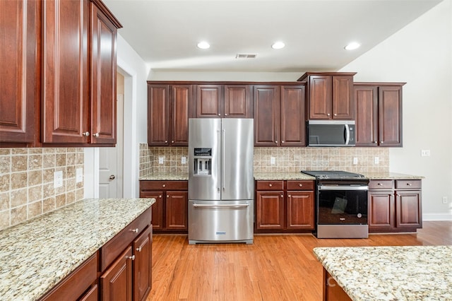 kitchen featuring light wood-type flooring, stainless steel appliances, and tasteful backsplash